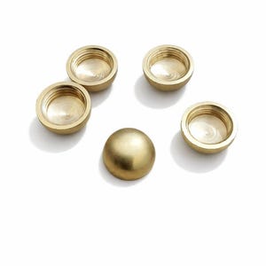 May include: Five brass hardware components are displayed against a white backdrop. Four are cup-shaped with threaded interiors, and one is a rounded dome. The pieces have a polished, reflective surface.