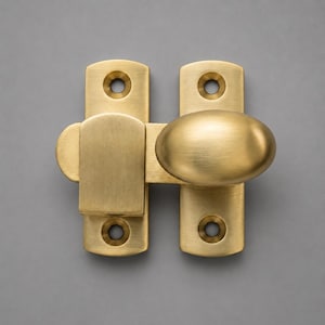 May include: A brushed brass gate latch featuring a rectangular mounting plate with two screw holes, a sliding bolt mechanism, and an oval-shaped knob handle. The hardware has a smooth, matte metallic finish and a clean, functional design.