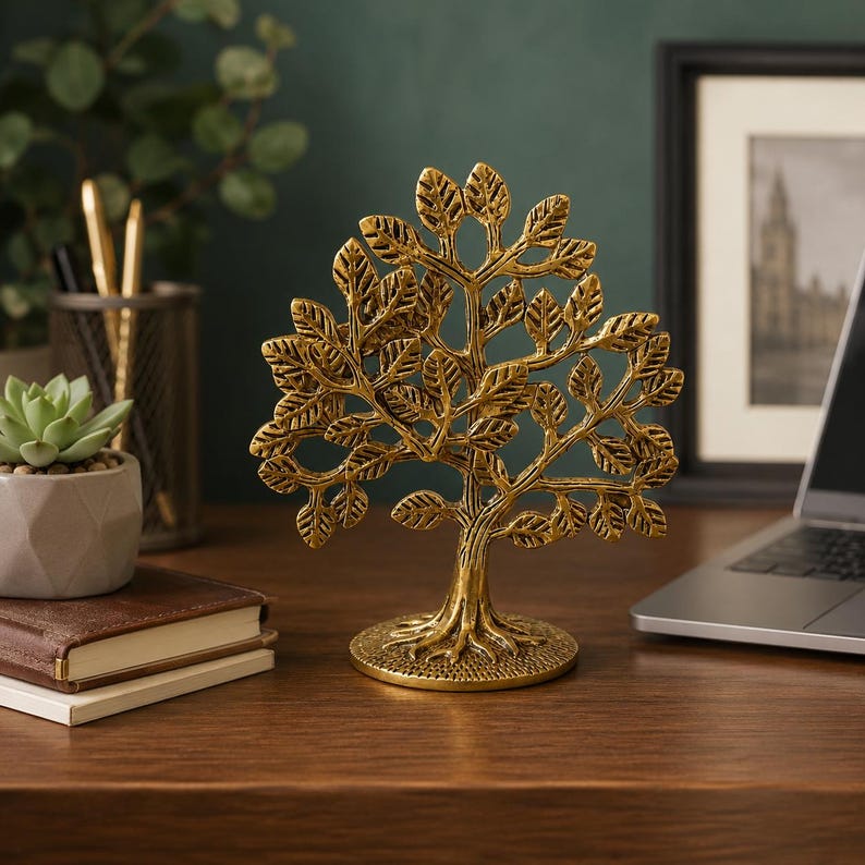 May include: A gold-colored metal sculpture of a tree with a textured trunk, exposed roots, and numerous detailed leaves. The tree stands on a circular base and features a symmetrical branch structure with a metallic finish and dark highlights.