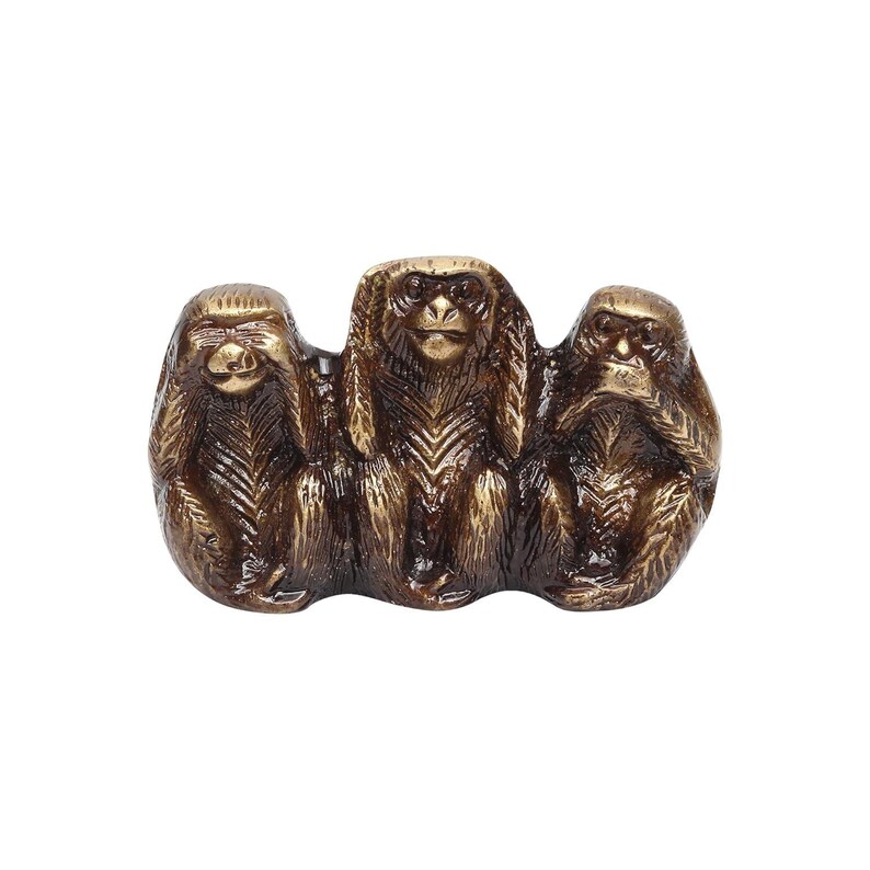 May include: A bronze-colored sculpture depicting the three wise monkeys: see no evil, hear no evil, and speak no evil. The monkeys are sitting side-by-side, with their hands covering their eyes, ears, and mouth. The sculpture has a textured surface.