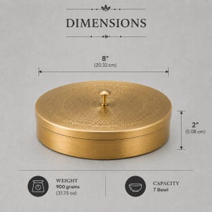 May include: A round, gold-colored metal container with a lid and a central knob handle. The lid features an intricate, etched pattern. Dimensions are 8 inches in diameter and 2 inches in height. The item weighs 31.75 ounces and has a 7-bowl capacity.