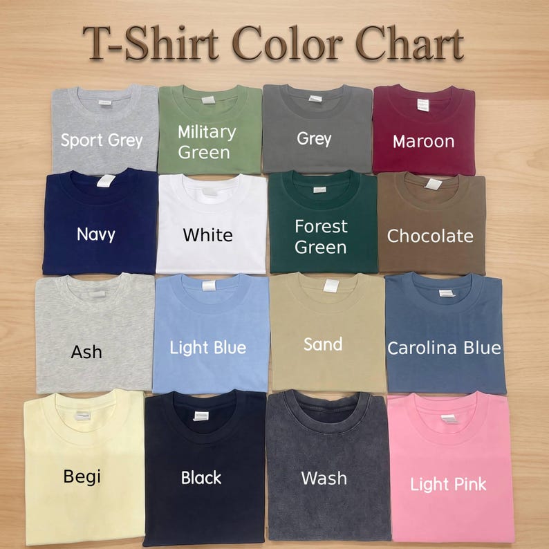 Puede incluir: Una carta de colores de camisetas que muestra diecis&eacute;is camisetas de cuello redondo dobladas en varios colores s&oacute;lidos, incluyendo Sport Grey, Military Green, Grey, Maroon, Navy, White, Forest Green, Chocolate, Ash, Light Blue, Sand, Carolina Blue, Begi, Black, Wash y Light Pink.