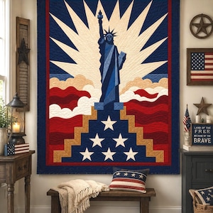 Puede incluir: Un edredón patriótico con la Estatua de la Libertad en azul, rojo y blanco. El diseño incluye un borde azul, líneas blancas radiantes y un patrón ondulado rojo y blanco. Es una decoración de pared.