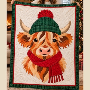 May include: A rectangular quilt featuring a central appliqué of a Highland cow wearing a green plaid knit hat with a red pom-pom and a red textured scarf. The cow has brown fur, curved horns, and is set against a cream background with swirling stitching.