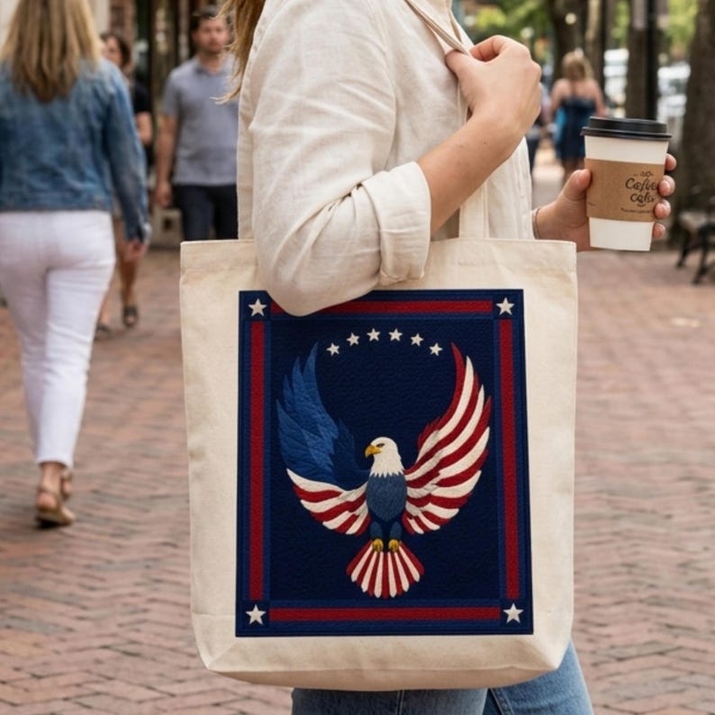 Puede incluir: Un bolso tote de color crema con un dise&ntilde;o patri&oacute;tico. El dise&ntilde;o incluye un fondo azul con un borde rojo y blanco, un &aacute;guila con alas rojas, blancas y azules y seis estrellas blancas. El bolso lo lleva una persona.