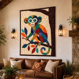 Puede incluir: Un edred&oacute;n de pared rectangular que presenta un mono estilizado compuesto por parches geom&eacute;tricos vibrantes y multicolores. El mono est&aacute; posado sobre una rama de &aacute;rbol marr&oacute;n oscuro sobre un fondo crema texturizado, con un borde de tela marr&oacute;n.