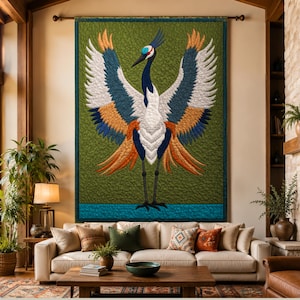 Könnte beinhalten: Ein großer rechteckiger Wandbehang-Quilt mit einem zentralen Kranich mit weit ausgebreiteten Flügeln. Der Vogel hat einen weißen Körper, dunkelblaue und orangefarbene Flügelfedern und eine rote Krone. Der Hintergrund ist olivgrün mit einem türkisfarbenen Band.