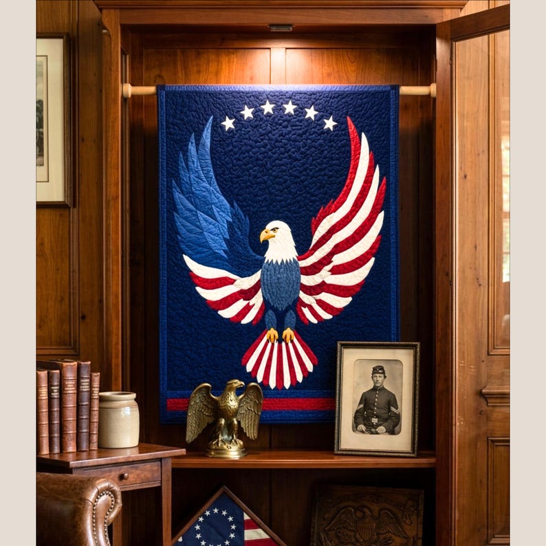 Puede incluir: Un tapiz de pared patri&oacute;tico con un dise&ntilde;o de &aacute;guila en rojo, blanco y azul. El &aacute;guila tiene las alas extendidas y estrellas encima. El tapiz se exhibe en un armario de madera con otros objetos decorativos.