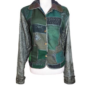May include: A patchwork jacket in shades of green, with long sleeves and a button-up front. The jacket features a variety of fabric patterns and textures, including floral and geometric designs. The collar is a mix of brown and green.