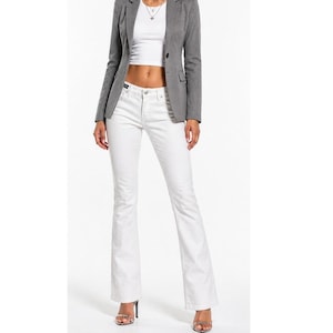 May include: A gray blazer with a two-button closure, paired with a white crop top and white flared jeans. The outfit is completed with silver heels. The ensemble is a modern take on casual wear.