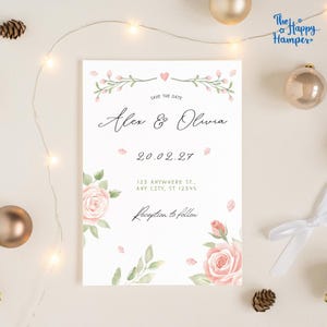 Könnte beinhalten: Eine weiße Hochzeitseinladung mit Aquarell-Blütenakzenten. Der Text lautet "Alex & Olivia" und "Save the Date" mit dem Datum 20.02.27. Enthält Adresse und "Reception to follow". Dekoriert mit rosa Rosen und grünen Blättern.