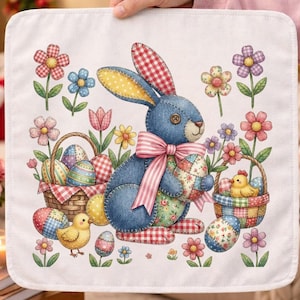 Puede incluir: Un paño decorativo cuadrado blanco con un conejito azul que sostiene un huevo de Pascua decorado. El conejito tiene detalles de patchwork y un lazo rosa. Flores coloridas y huevos de Pascua rodean al conejito, con dos cestas llenas de huevos y un pollito.