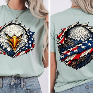 May include: A pale green t-shirt with a graphic of an American bald eagle. The eagle's head and chest are visible, surrounded by a design incorporating the American flag's stars and stripes. The back of the shirt also features the eagle design.