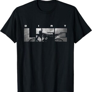 May include: A black short-sleeve t-shirt featuring the text DIRT LIFE in white capital letters. The word LIFE is printed in a large block font with a grayscale graphic of a dirt bike silhouette integrated into the letters against a cloudy background.