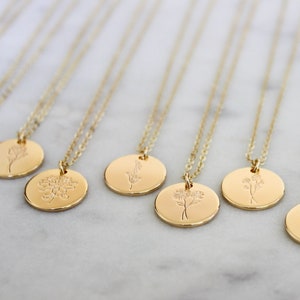 Peut inclure: Plusieurs colliers dor&eacute;s avec des pendentifs ronds. Chaque pendentif pr&eacute;sente un motif floral diff&eacute;rent. Les colliers sont dispos&eacute;s sur une surface en marbre blanc, mettant en valeur les d&eacute;tails d&eacute;licats des bijoux.