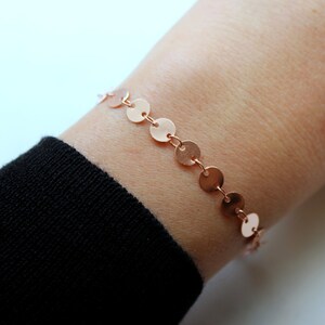 May include: A rose gold bracelet with a chain of connected round discs.