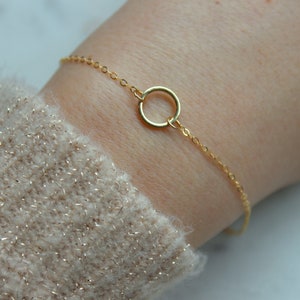 May include: A delicate gold chain bracelet with a simple circle pendant.