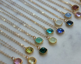 May include: A collection of gold necklaces with various colored gemstone pendants. The pendants are all oval-shaped and have a gold rim. The necklaces are arranged in a row, with the pendants getting progressively larger from left to right.