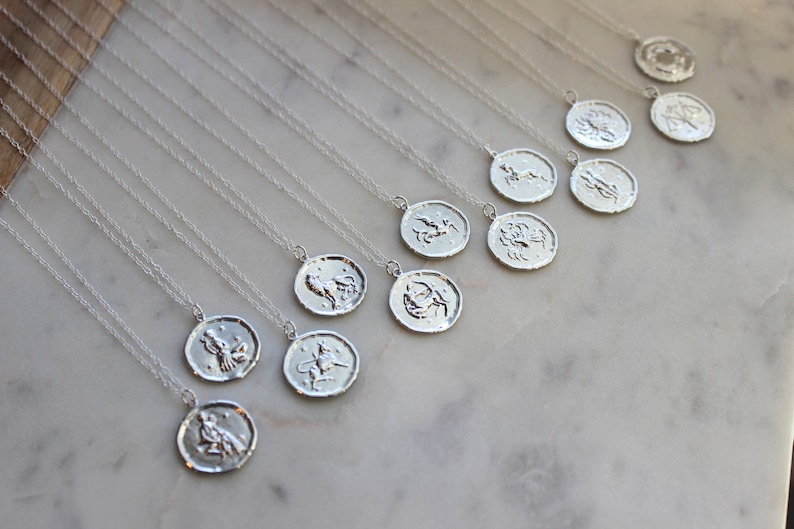 May include: A collection of silver necklaces with zodiac symbols on the pendants. Each pendant features a different zodiac sign, including Aries, Taurus, Gemini, Cancer, Leo, Virgo, Libra, Scorpio, Sagittarius, Capricorn, Aquarius, and Pisces.