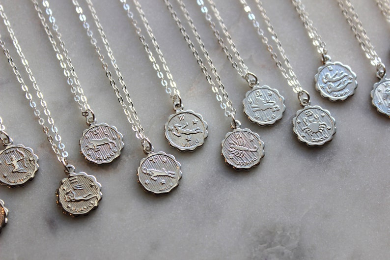 Puede incluir: Un conjunto de collares de plata con colgantes de signos del zod&iacute;aco. Cada colgante presenta un s&iacute;mbolo del zod&iacute;aco diferente, incluyendo Sagitario, Tauro, Virgo, Escorpio, C&aacute;ncer, y m&aacute;s.