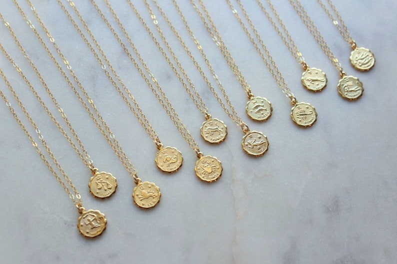 May include: A set of 12 gold zodiac necklaces with delicate chains and small round pendants featuring the astrological signs.
