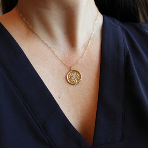 Pu&ograve; includere: Una collana con catena dorata con un ciondolo rotondo che presenta un design di scorpione dettagliato.