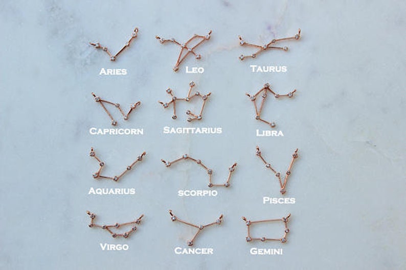 May include: Twelve gold zodiac constellation necklaces with small clear crystals. The constellations are Aries, Taurus, Gemini, Cancer, Leo, Virgo, Libra, Scorpio, Sagittarius, Capricorn, Aquarius, and Pisces.