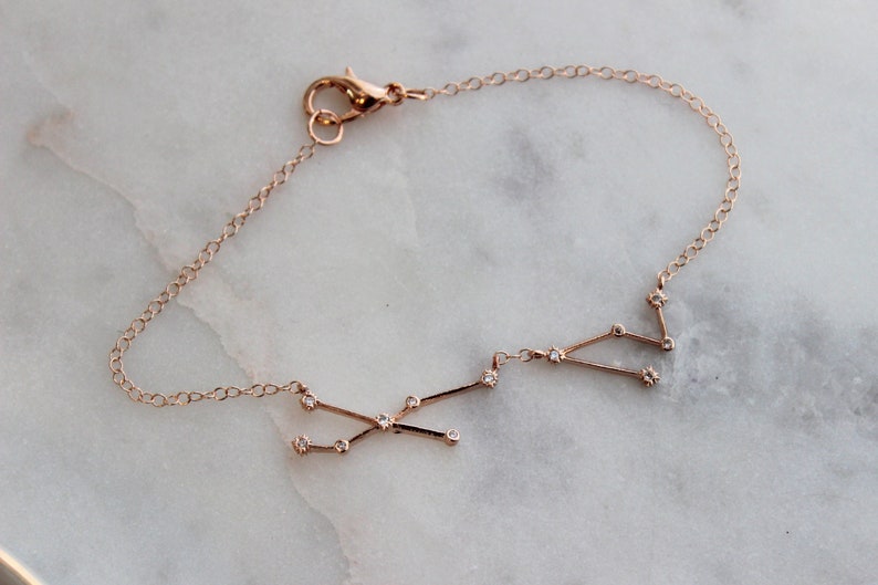 May include: A delicate gold chain bracelet with a constellation design featuring small sparkling diamonds.