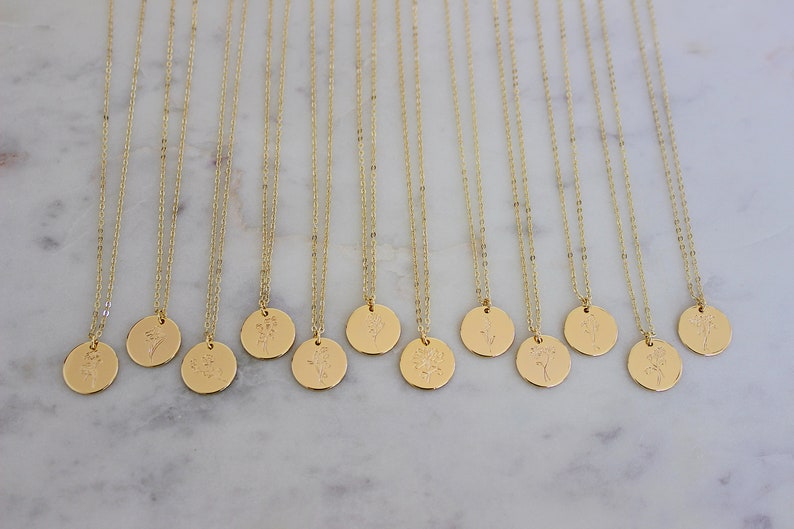 Peut inclure: Colliers dor&eacute;s avec des cha&icirc;nes d&eacute;licates et des pendentifs ronds. Chaque pendentif pr&eacute;sente un motif floral diff&eacute;rent. Les colliers sont pr&eacute;sent&eacute;s sur une surface en marbre blanc, cr&eacute;ant une pr&eacute;sentation &eacute;pur&eacute;e et &eacute;l&eacute;gante.