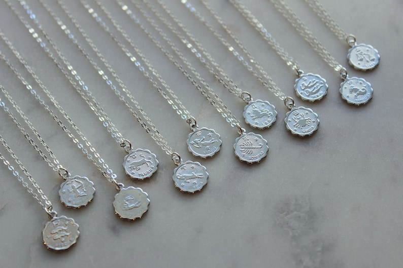 Puede incluir: Un conjunto de collares de plata con colgantes de signos del zod&iacute;aco. Cada collar presenta un s&iacute;mbolo del zod&iacute;aco diferente, incluidos Aries, Tauro, G&eacute;minis, C&aacute;ncer, Leo, Virgo, Libra, Escorpio, Sagitario, Capricornio, Acuario y Piscis.