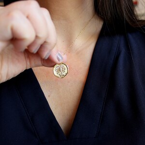 Pu&ograve; includere: Una collana d'oro con un ciondolo rotondo che presenta un design di scorpione dettagliato.