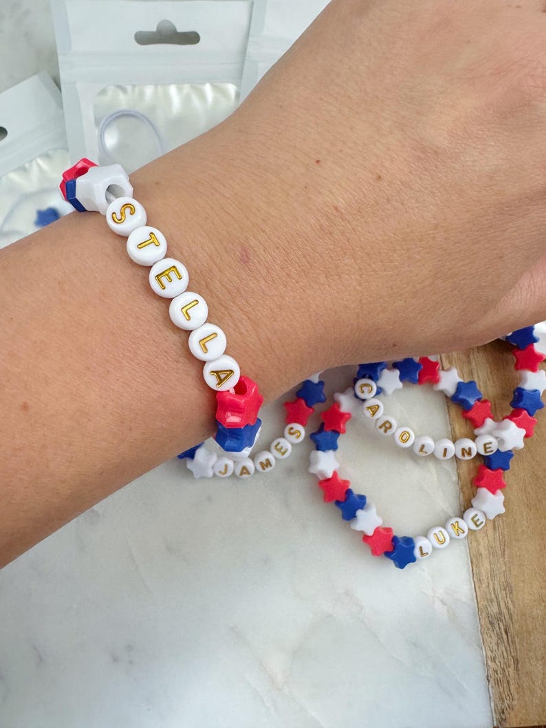 May include: Three colorful beaded bracelets with the names "Stella", "James", and "Caroline" and "Luke" spelled out in gold letters.