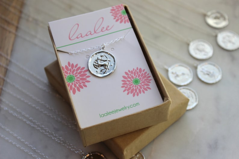 May include: A silver Sagittarius zodiac necklace in a brown gift box with a pink and green floral design. The box has the text "laalee" and "laaleejewelry.com" printed on it.