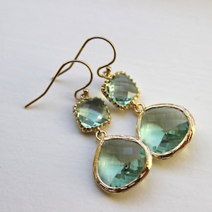 May include: Gold earrings with two teardrop-shaped light blue crystals.