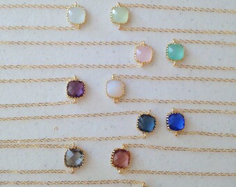 May include: A set of 10 gold chain necklaces with different colored square-shaped gemstone pendants. The pendants are in shades of blue, green, purple, pink, and white.
