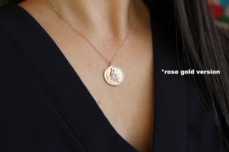 May include: A rose gold necklace with a round pendant featuring a detailed design of a woman sitting. The pendant is on a delicate chain.