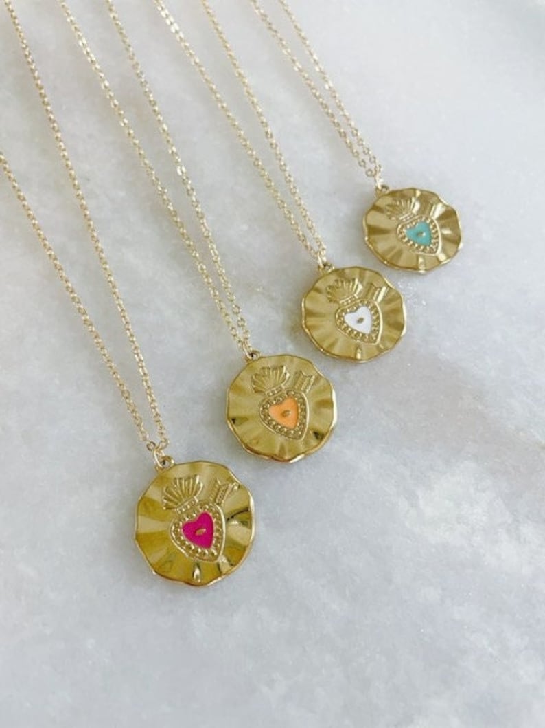 K&ouml;nnte beinhalten: Vier goldene Halsketten mit einem herzf&ouml;rmigen Anh&auml;nger. Jeder Anh&auml;nger hat ein Herz aus farbigem Emaille: T&uuml;rkis, Wei&szlig;, Orange und Rosa.
