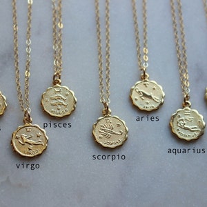 May include: Gold zodiac necklaces with pendants featuring the astrological signs: Taurus, Pisces, Virgo, Scorpio, Aries, Gemini, and Aquarius.