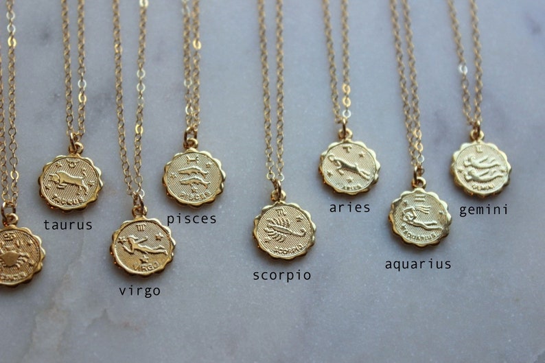 May include: Gold zodiac necklaces with pendants featuring the astrological signs: Taurus, Pisces, Virgo, Scorpio, Aries, Gemini, and Aquarius.