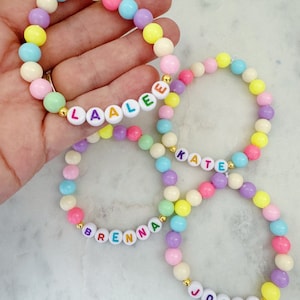 May include: Four colorful beaded bracelets with the names Laale, Kate, Brenna, and Josie spelled out in colorful letters.