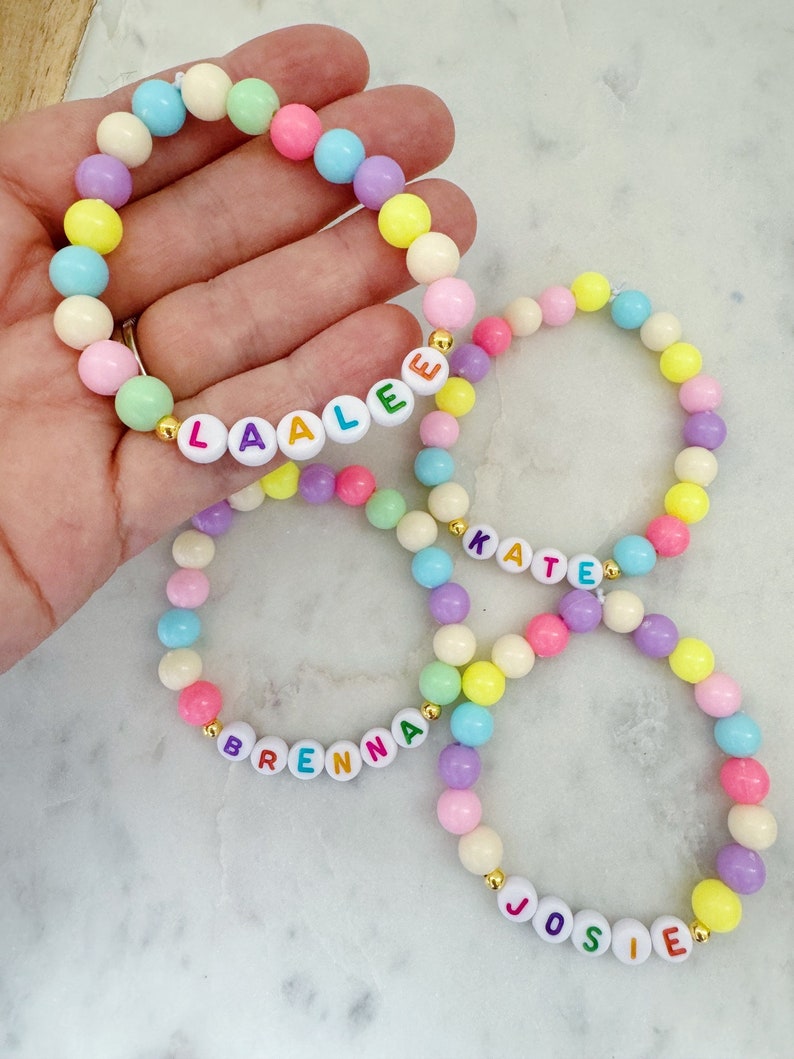 May include: Four colorful beaded bracelets with the names Laale, Kate, Brenna, and Josie spelled out in colorful letters.