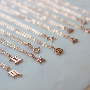 May include: A set of 12 gold-toned zodiac necklaces with delicate chains. Each necklace features a different zodiac symbol, including Gemini, Virgo, Pisces, Taurus, and Libra.