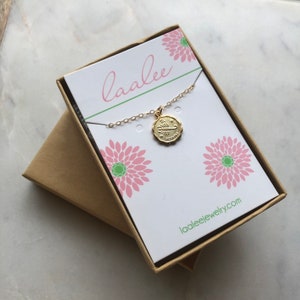 May include: Gold Scorpio zodiac necklace in a white box with pink flowers and the text "laalee" and "laaleejewelry.com".