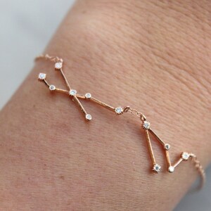 May include: A rose gold bracelet with a constellation design featuring small clear stones.