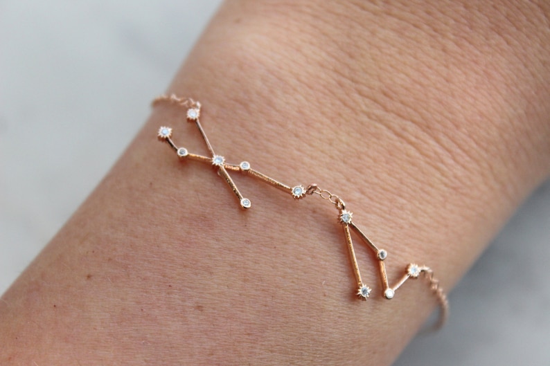 May include: A rose gold bracelet with a constellation design featuring small clear stones.