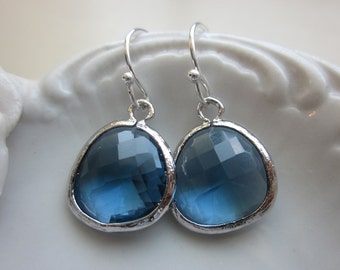 May include: A pair of silver dangle earrings with a dark blue faceted gemstone. The earrings have a simple, elegant design.