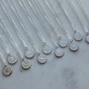 Puede incluir: Un conjunto de doce collares de plata con colgantes de signos del zod&iacute;aco. Cada collar presenta una delicada cadena de plata y un peque&ntilde;o colgante redondo con un s&iacute;mbolo del zod&iacute;aco.