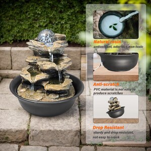 May include: A multi-tiered water fountain with a rock design, creating a cascading waterfall. The fountain has a black bowl base and a decorative glass ball. The image highlights the fountain's natural resin, anti-scratch, and drop-resistant qualities.