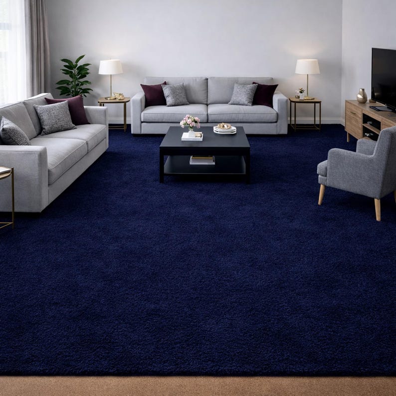 May include: A navy blue shag rug covers the floor of a living room. Two gray sofas with decorative pillows face each other, with a black coffee table in the center. Two lamps sit on side tables, and a gray armchair is in the corner.