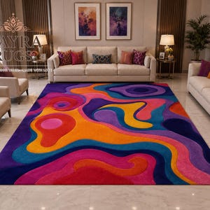 May include: A rectangular area rug featuring a vibrant, multi-colored abstract pattern with fluid, organic shapes in shades of purple, orange, pink, yellow, and blue. The rug displays a high-low texture and is positioned in a living room setting.